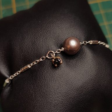 Un bel exemple de personnalisation de votre Bijou permanent avec un charms en or et diamant noir et un charms perle naturelle qui coulisse.